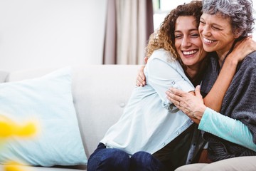 Smiling mother and daughter hugging at home