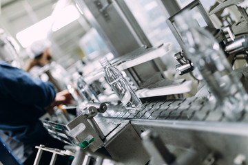 Robotic factory line for processing and bottling of pure spring water into canisters and bottles. Selective focus. Short depth of field.