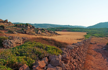 Menorca, Balearen: rode zand- en tarwevelden op het pad naar Cala Pregonda, de baai vergelijkbaar met de planeet Mars, op 15 juli 2013