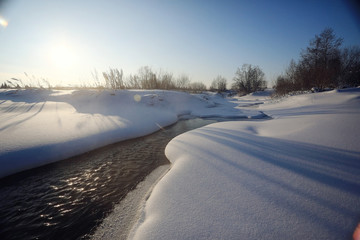 Fototapeta na wymiar March on the creek snow ice water