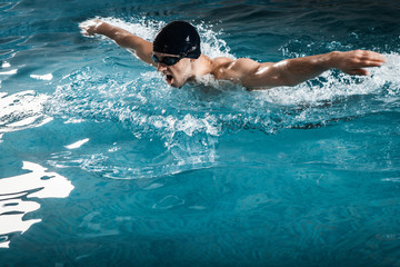 Fototapeta na wymiar Muscular young man swims the butterfly