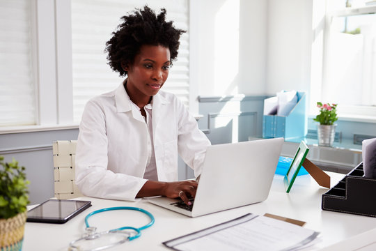Black female doctor wearing white coat at work in an office