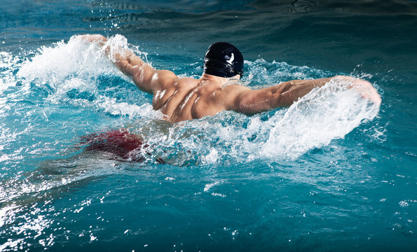Young healthy man with muscular body swims