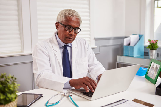 Senior black male doctor in white coat working in an office