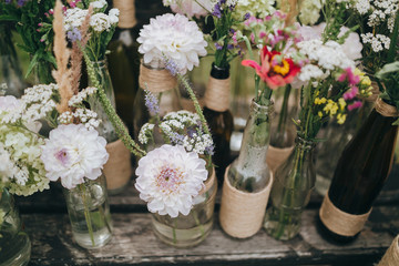 flowers and herbs in glass bottles standing on an old wooden bench in the garden