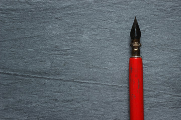 Vintage red pen on dark stone background