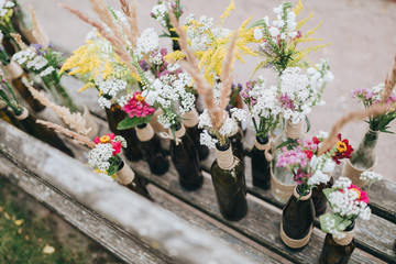 flowers and herbs in glass bottles standing on an old wooden bench in the garden