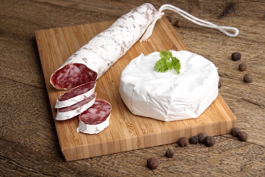 Traditional sliced salami on wooden board with brie Camembert