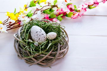 Obraz na płótnie Canvas Beautiful Easter background with flowers and nest with eggs on white painted boards