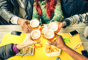Group of friends cheers with beer cafe interior scene - Multiracial hands holding glasses of Pils...