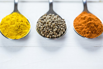 Beautiful colorful spices in an iron spoon on old wooden table white. Free space for your text