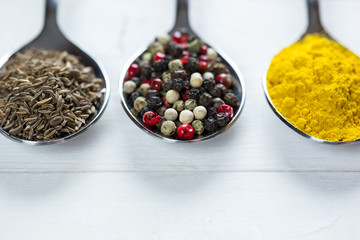 Beautiful colorful spices in an iron spoon on old wooden table white. Free space for your text