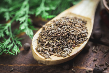beautiful photo of cumin in wooden spoon on the background of the old wooden Desk and dill