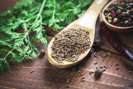 beautiful photo of cumin in wooden spoon on the background of the old wooden Desk and dill