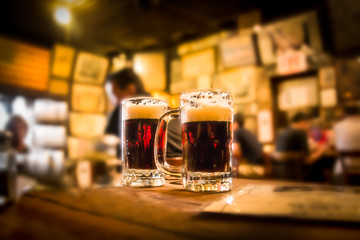 Defocused bar blur with 2 mugs of beer in focus