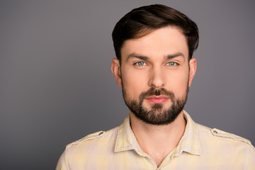 Portrait of minded strict handsome  brunet with beard on gray ba