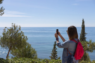 Naklejka premium Woman taking photo of nature and sea