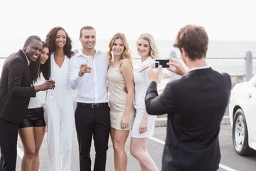 Well dressed people taking pictures next to a limousine