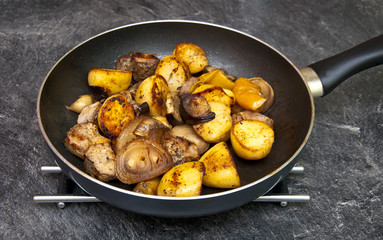 Fried mixture of potatoes, meat, mushrooms, onion and pepper in pan