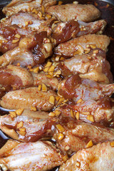 Marinated chicken wings on a black pan. Selective focus