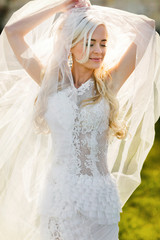 Fototapeta na wymiar gently blonde bride in lace dress backgroung wall in garden