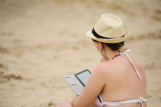 woman reading tablet reader on the beach