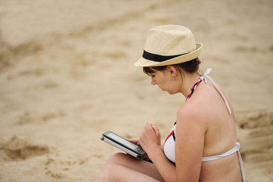 woman reading tablet reader on the beach
