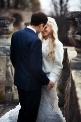 blonde bride and brunette groom walking near  old castle