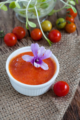 Homemade tomato sauce in white bowl on hemp sack with raw tomatoes