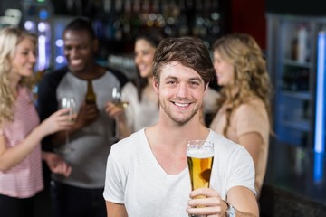 Smiling man showing a beer with his friends