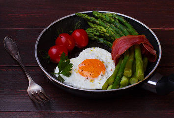 Asparagus in a pan with bacon and fried egg