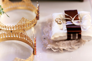 gold crown on white table near lace pillow