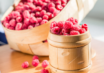 Sweet raspberry in a basket in a wooden bank on the table