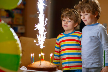 Little kid boys celebrating birthday with cake and candles