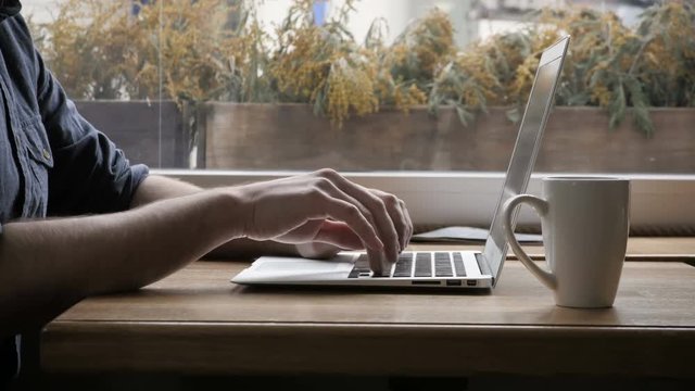 Silhouette of Happy Young Man Freelancer with Modern Laptop in Cafe taking Cup of Coffee