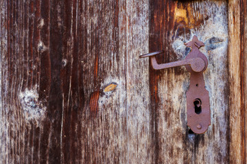 Rusty vintage door handle on an old wooden door