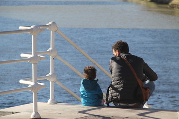 Padre e hijo sentados frente al río