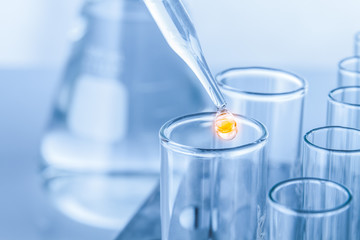 Laboratory pipette with drop of liquid over glass test tubes