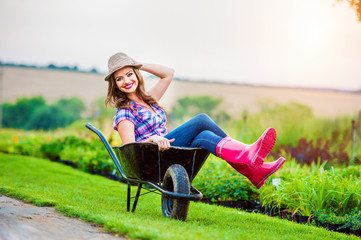 Woman sitting in wheelbarrow in sunny green garden