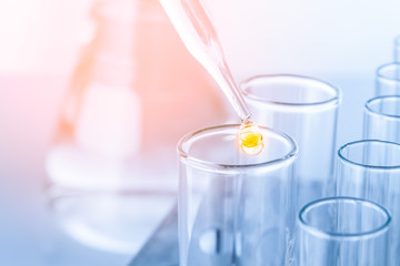 Laboratory pipette with drop of liquid over glass test tubes