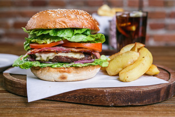 Fresh burger in bun with sesame with lettuce, tomato, beef and bacon.