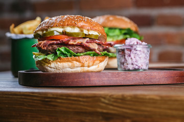 Fresh burger in bun with sesame with lettuce, tomato, beef and bacon.