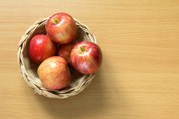 Red apple in basket on wood background