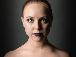 Beautiful woman with smoky eyes make-up and dark lips on a dark background