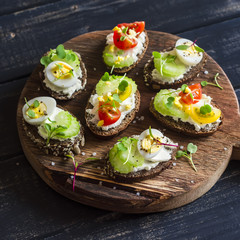 Sandwiches with soft cheese, quail eggs, cherry tomatoes and celery. Delicious healthy snack or Breakfast. On a wooden rustic board