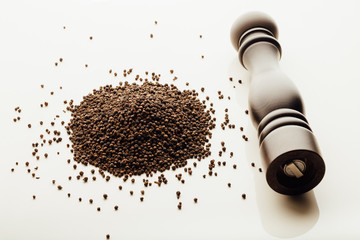 pepper mill and peppercorns heap, white background