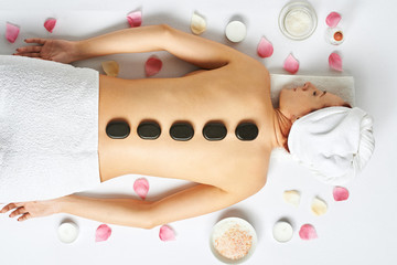 Woman having hot stones on her back in spa salon