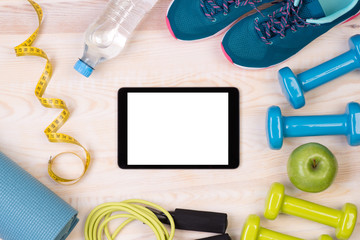 Fitness equipment on wooden background with a tablet