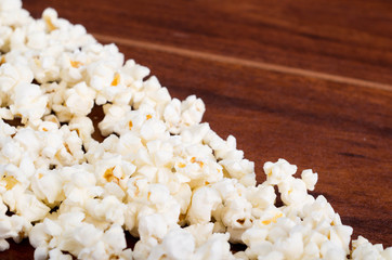 Closeup pile of white fluffy popcorn lying mixed together on wooden surface