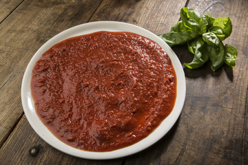 Sugo e basilico su piatto di porcellana posato su tavolo in legno